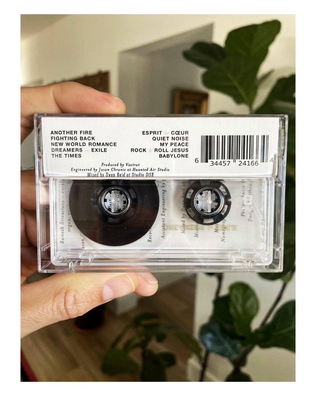 Cassette tape held in a hand with a blurred indoor background